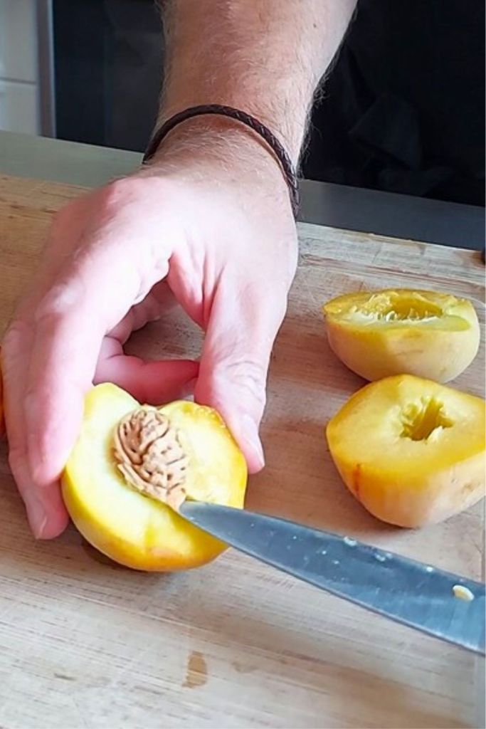 Removing peach pit using paring knife - after vertical cut.