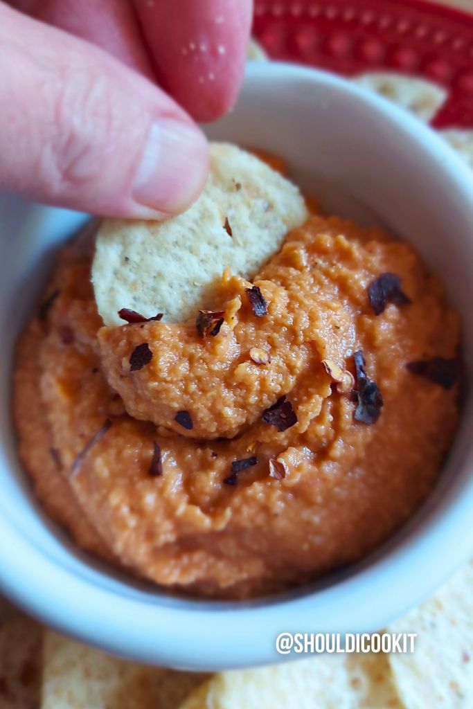 Scooping nacho hummus dip with a chip